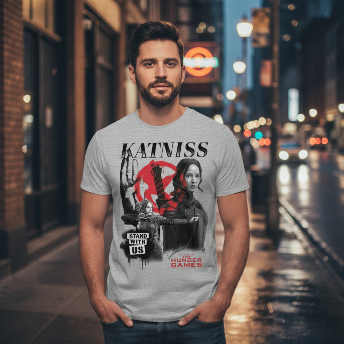 MAN WEARING Gray t-shirt with 'Katniss' graphic design featuring a character holding a bow and arrow, with text 'Stand With Us' and 'The Hunger Games' HGAM579S, HGAM579M, HGAM579L, HGAM579XL, HGAM579XXL, HGAM579XXXL, HGAM579XXXXL, HGAM579XXXXXL