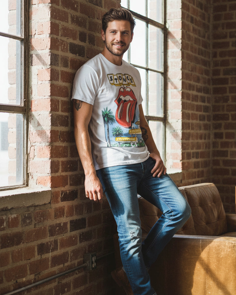Man wearing a Rolling Stones t-shirt leaning against a brick wall.